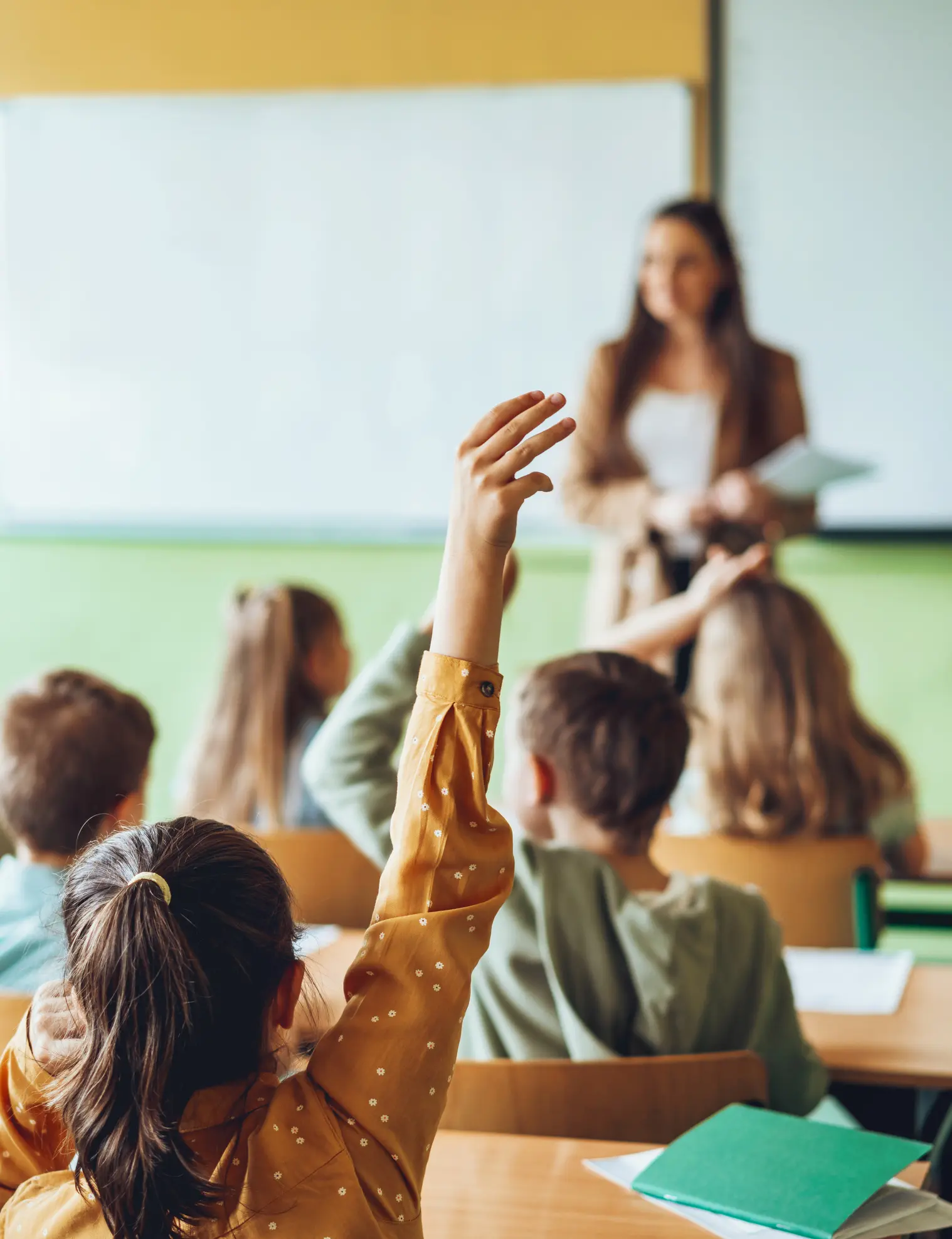 school girl in classroom putting up hands for asking questions